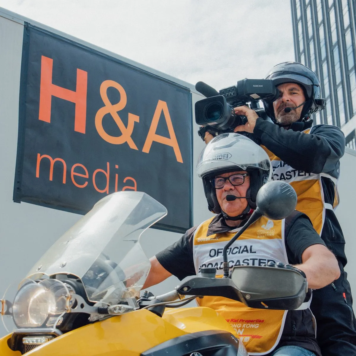 Camera operator filming from the back of the broadcast motorbike under the H&A Media banner