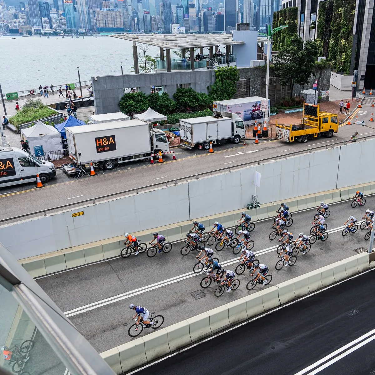 The peloton passing the H&A Media production trucks on the Hong Kong waterfront