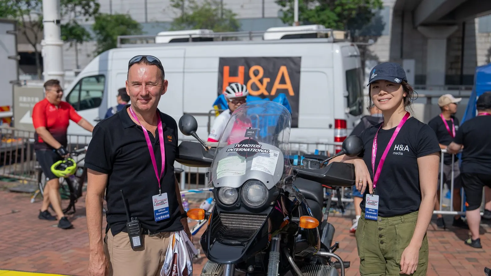 Two H&A Media crew in official broadcaster accreditation beside the TV motorbike and the H&A production van at the Hong Kong Cyclothon