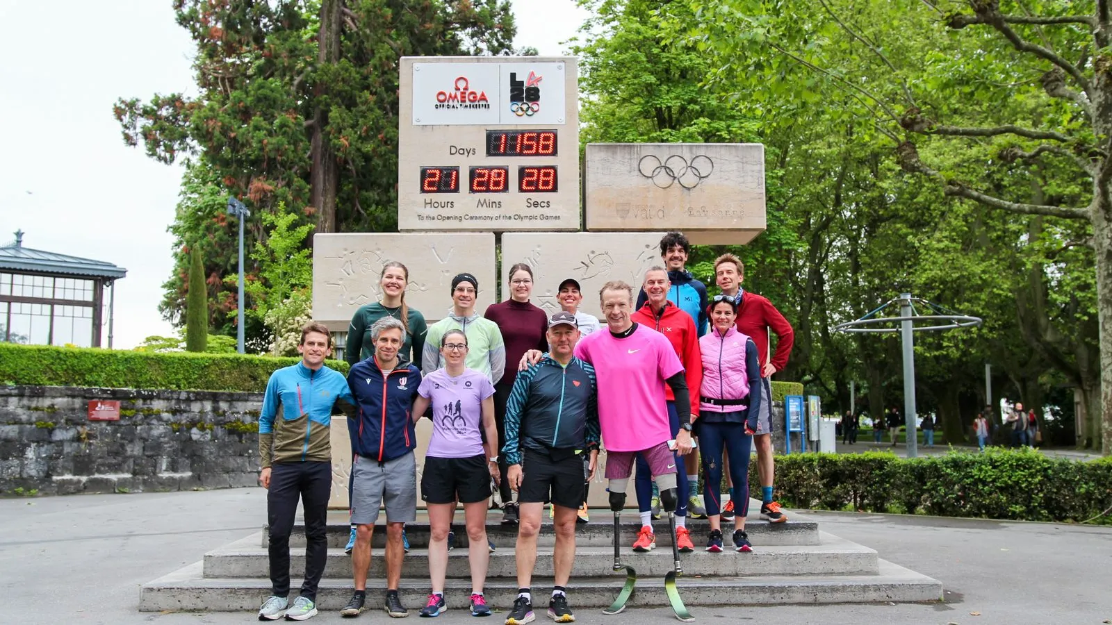A group of runners, one on a running blade, gathered under the Olympic countdown clock in Lausanne after a morning run
