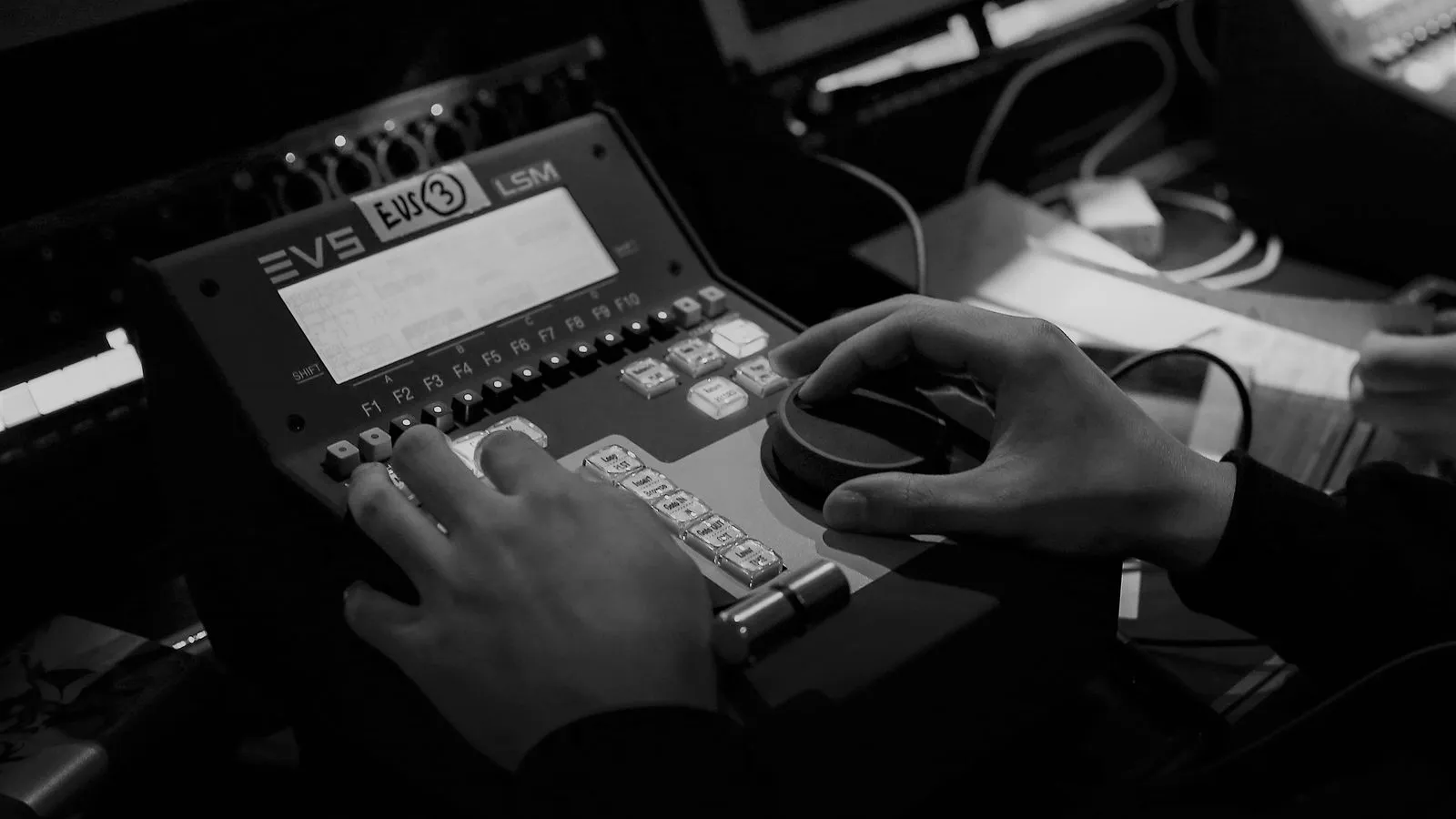 Hands working an EVS replay desk in the outside-broadcast gallery, logging notes alongside